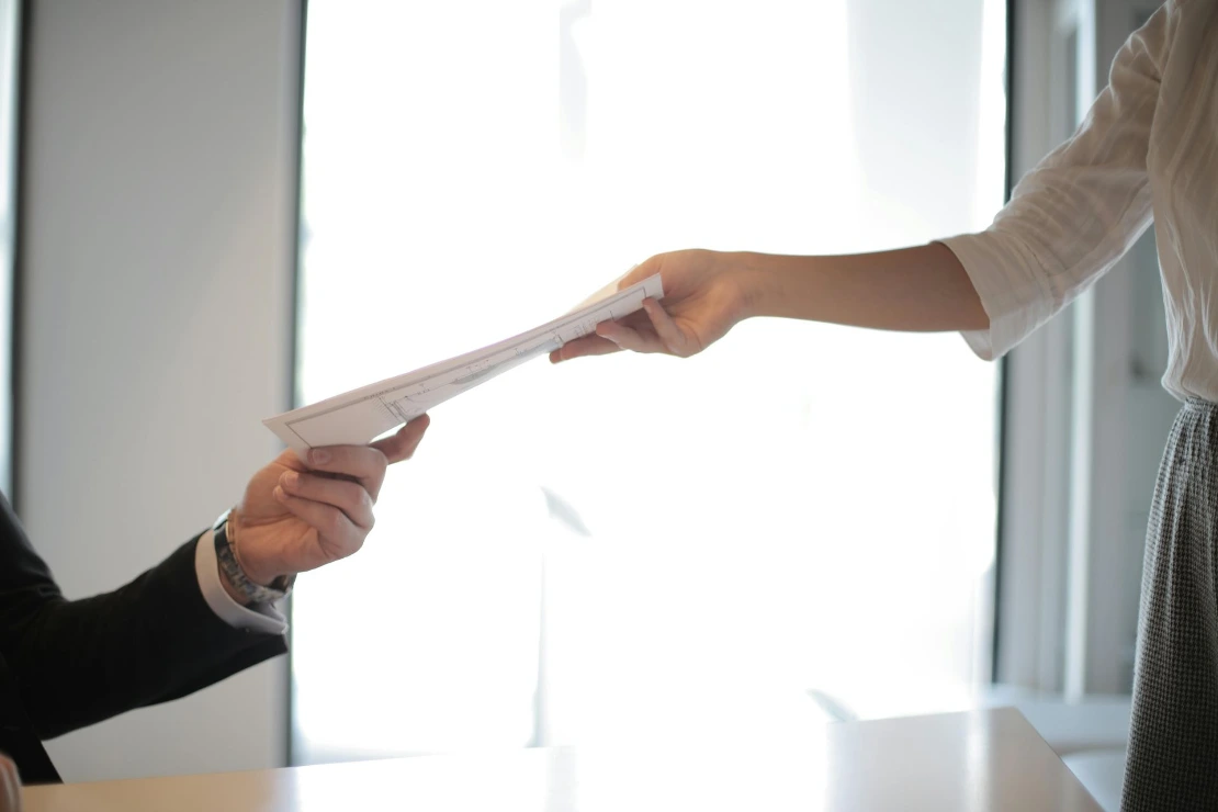 Documents being handed to another person, representing project handover